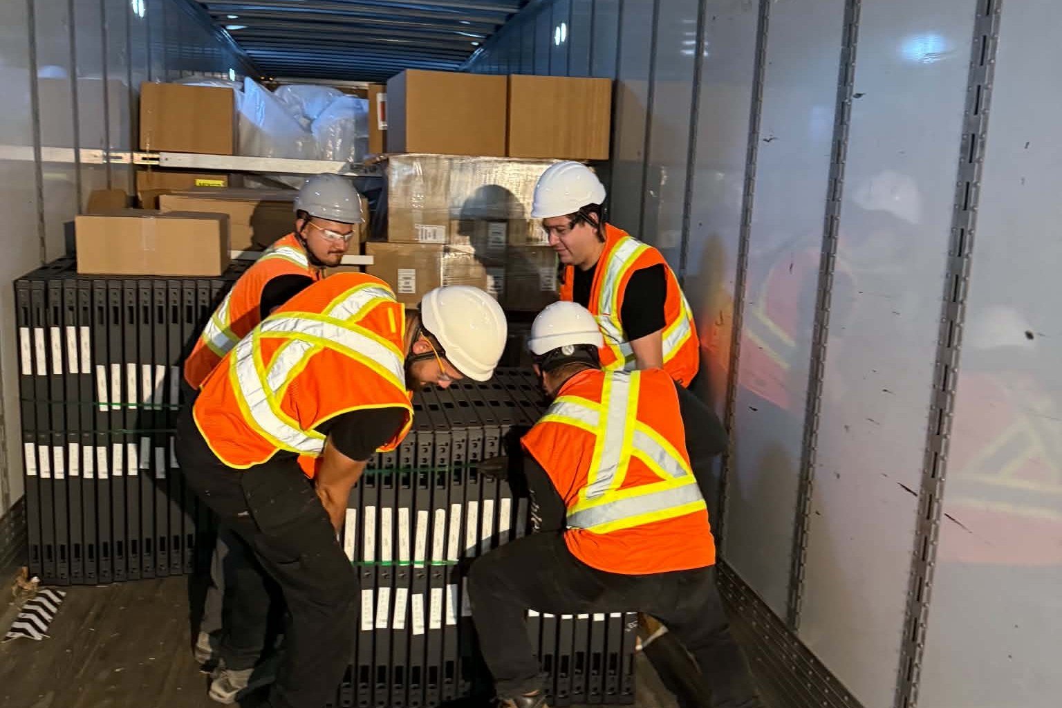 The SOIS crew in safety vests and hard hats handling wall system components inside a delivery truck